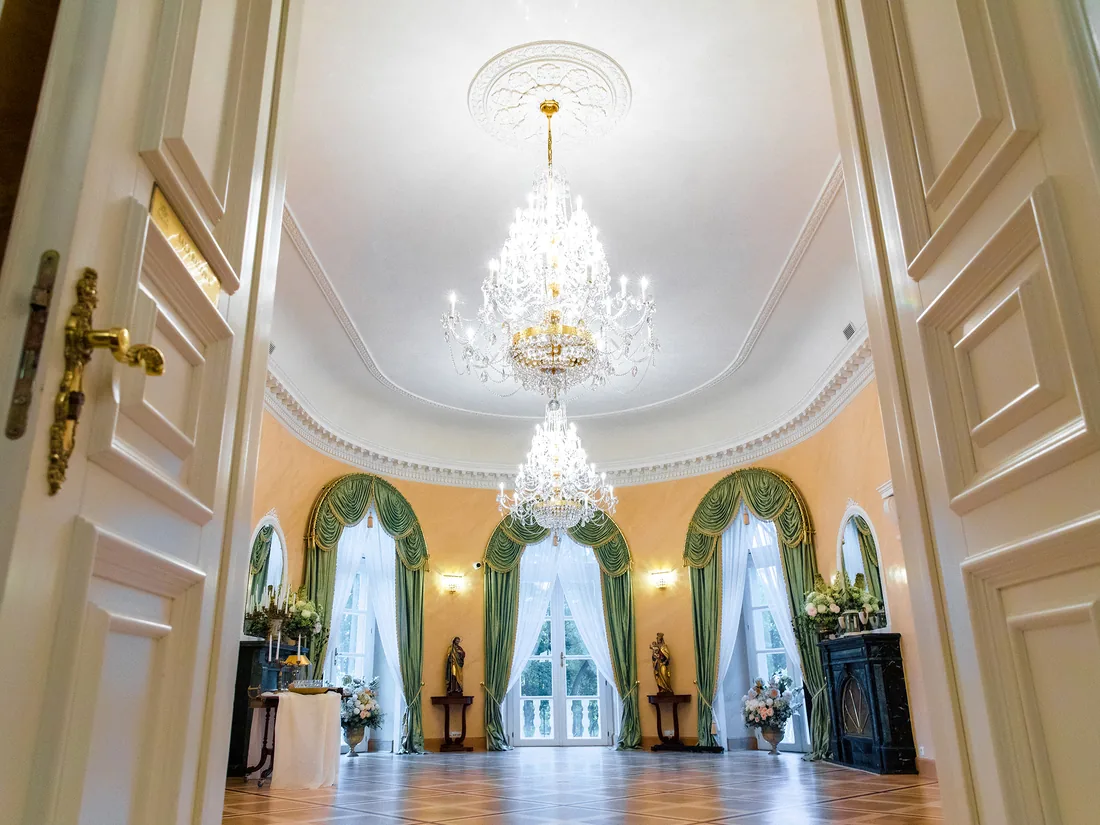 A palace room with green drapes and a chandelier