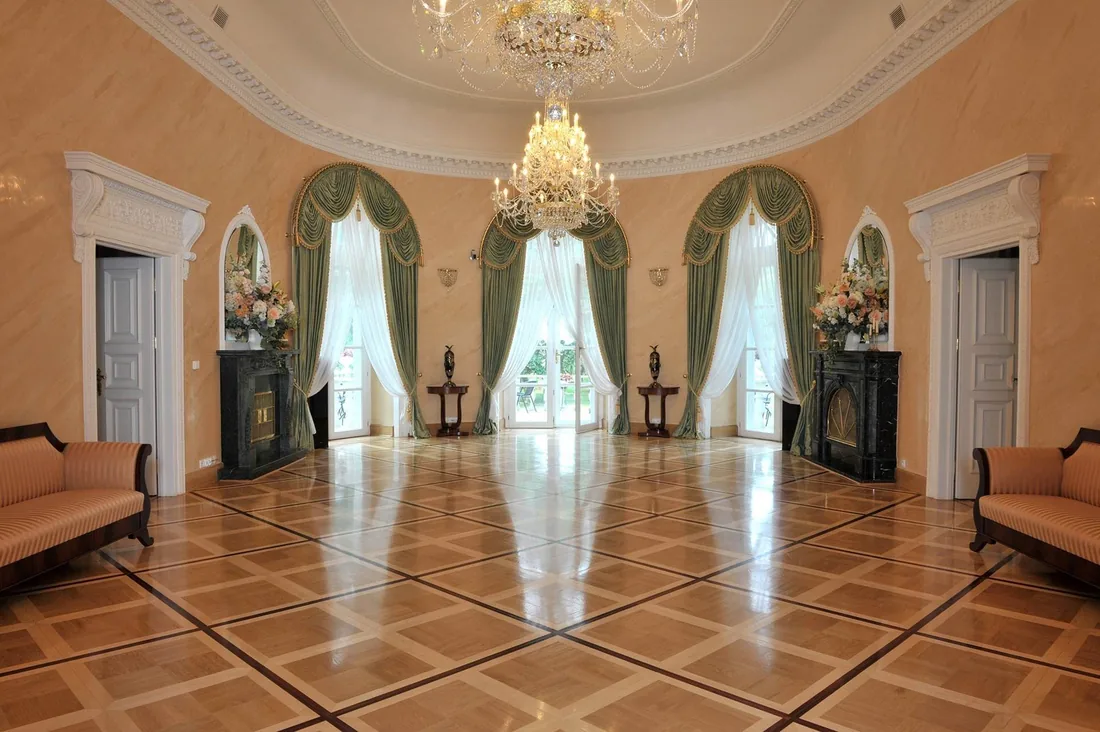 Sala balowa pałacu z żyrandolem i arkadowymi oknami